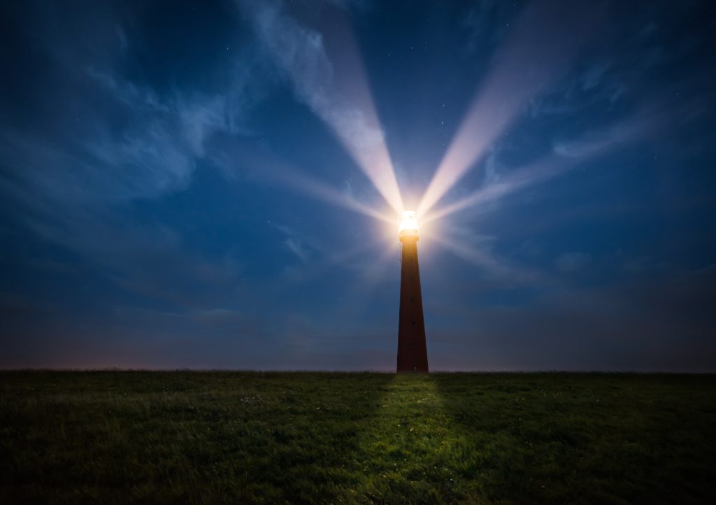 A lighthuse casts its beams on a dark night