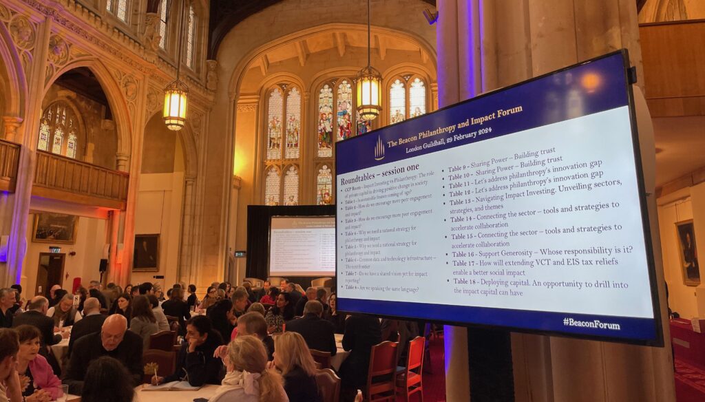 An image of participants at the Beacon Forum sitting talking at tables in the Guildhall in London